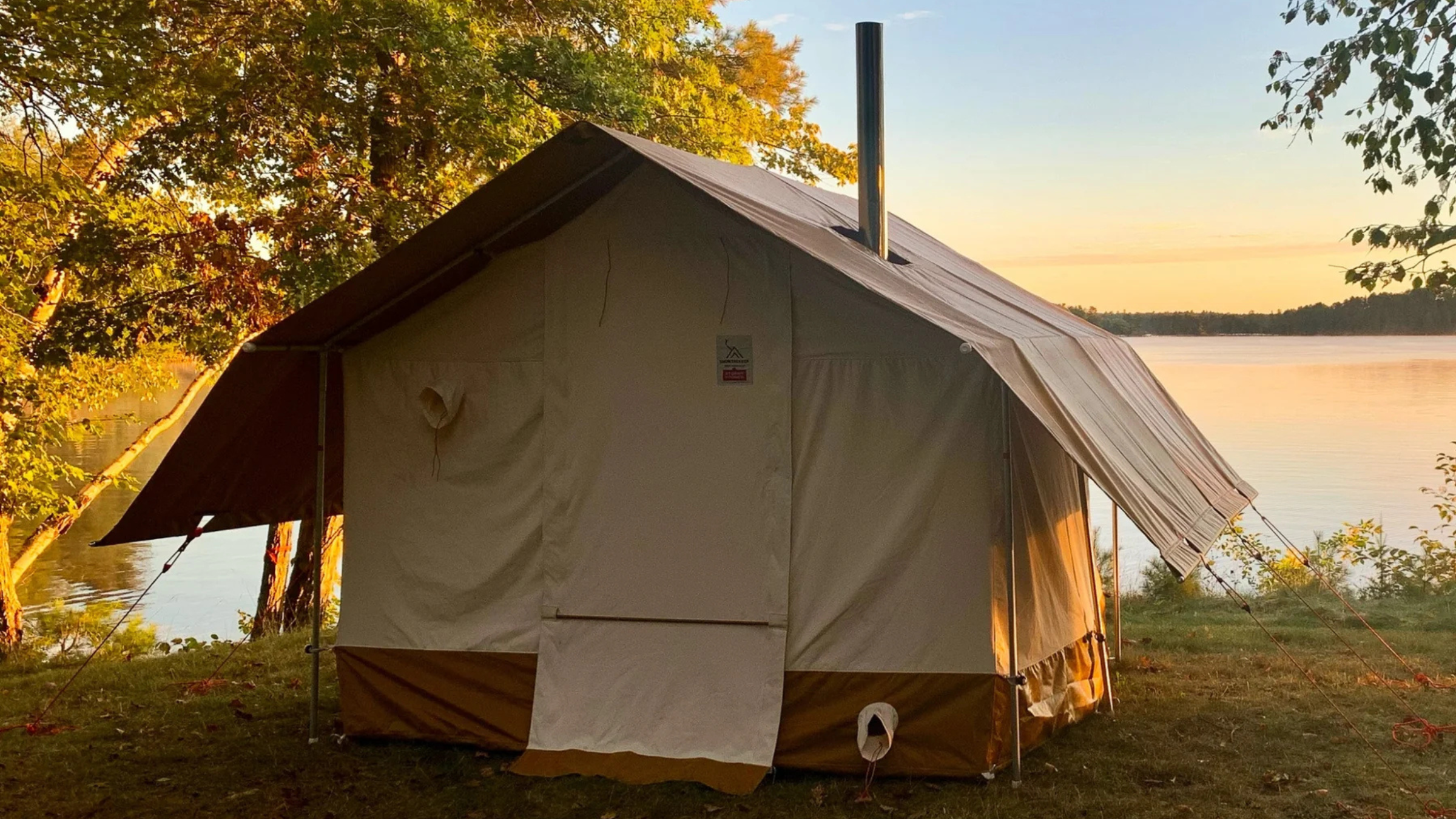 tan-colored home sauna tent from Snowtrekker outside in front of lake and trees
