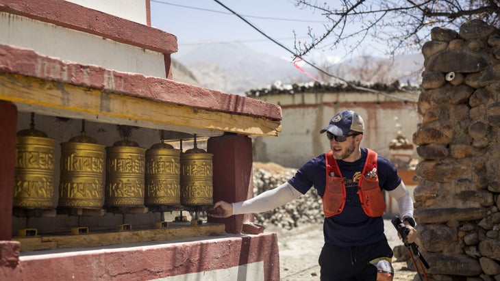 a man touching golden prayer wheels in Nepal