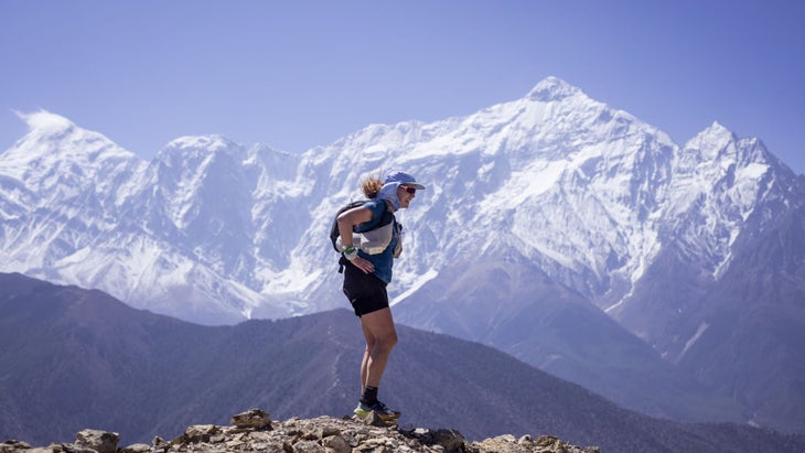 a woman stands on top of a mountain in Nepal