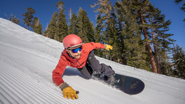 snowboarder leans into turn on corduroy