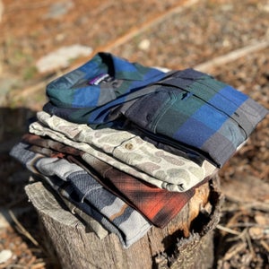 Feature image showing some of the Best Performance Flannels stacked on a log