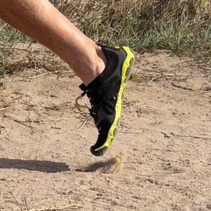 runner's legs in full stride on a trail wearing Vibram FiveFingers
