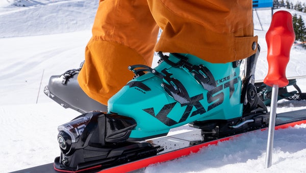 Closeup of turquoise Kastle ski boot clicked into ski on snow
