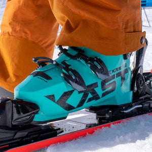Closeup of turquoise Kastle ski boot clicked into ski on snow
