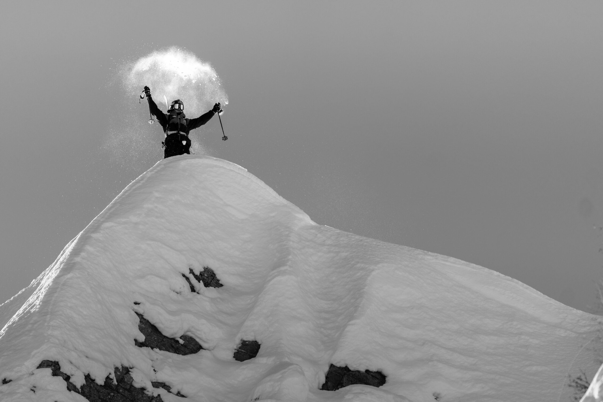 Skier on top of a ridge with arms up