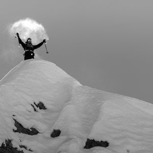 Skier on top of a ridge with arms up