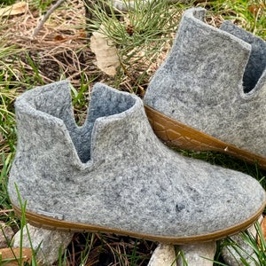 Closeup of grey Glerups wool boot slippers on grass