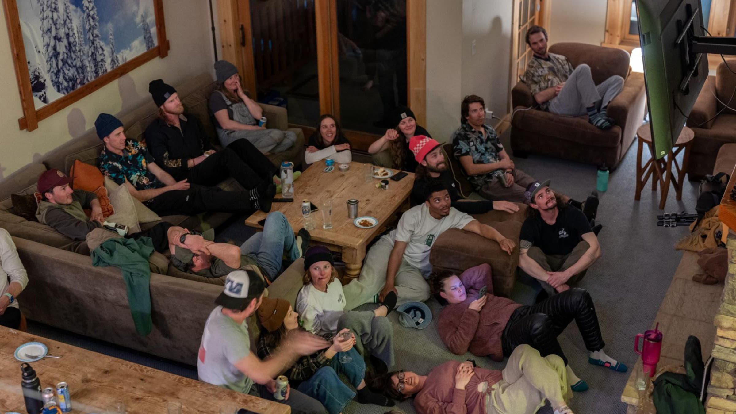 group of snowboarders gather indoors to watch a movie
