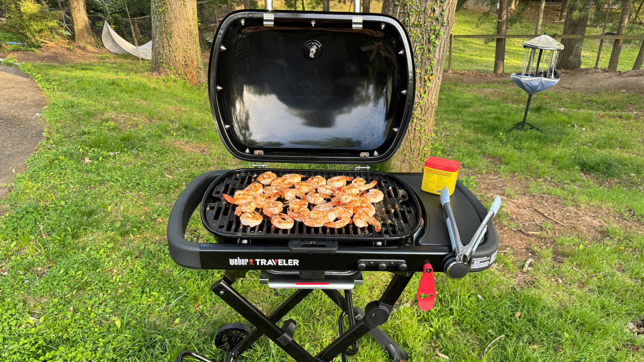 Weber traveler grill outside with shrimp cooking on it during tailgating session