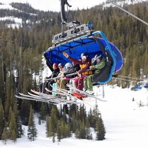 Skiers wearing the best budget ski jackets in colorful options riding a ski lift