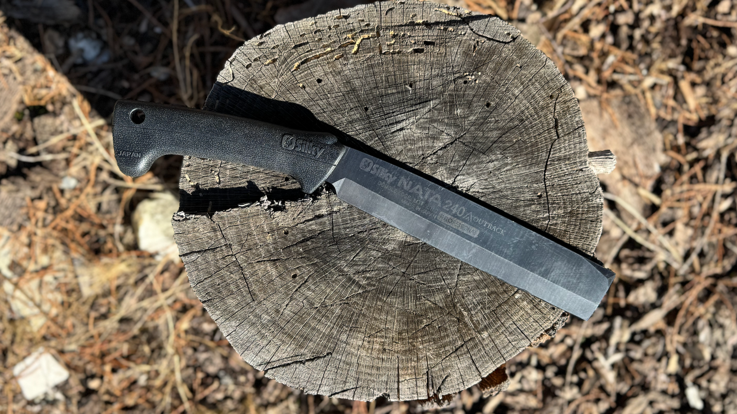 a machete-style field hatchet rests on top of tree stump outside, best hatchets