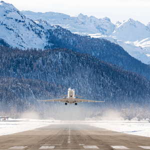 how to fly with your skis showing a plane landing in front of a snowy mountain backdrop