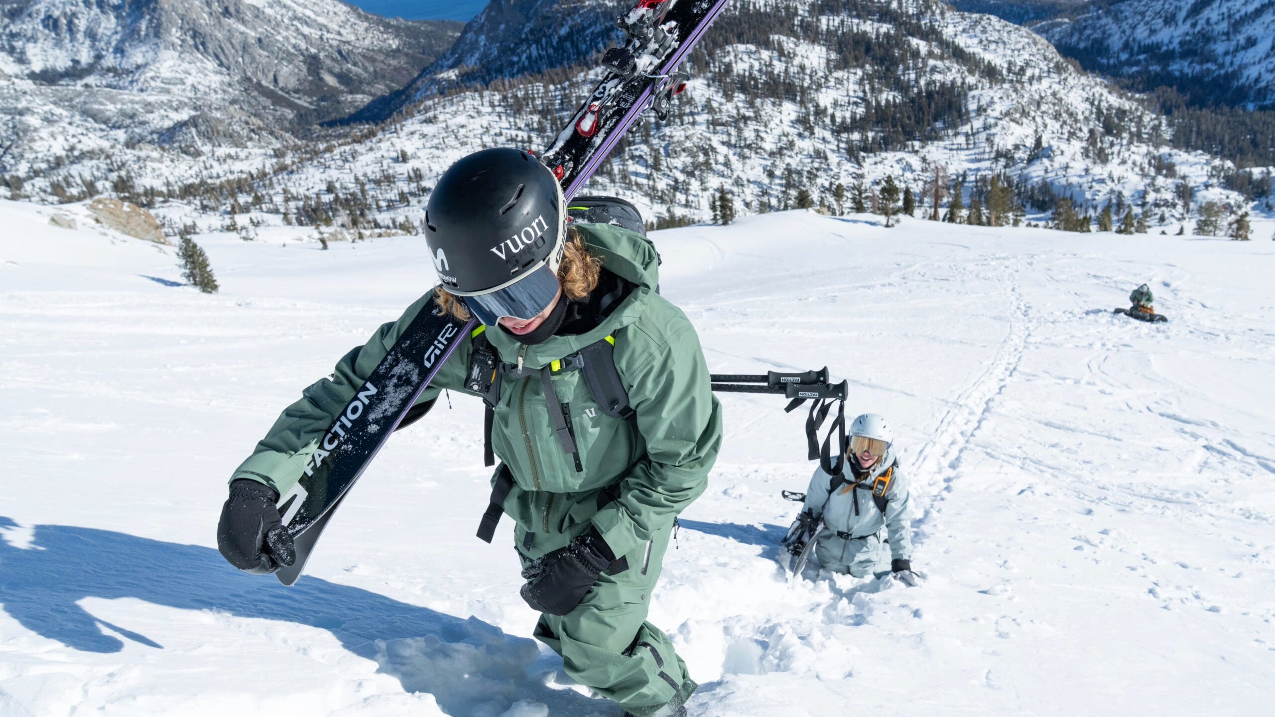 skiers climbing up a hill in vuori ski gear