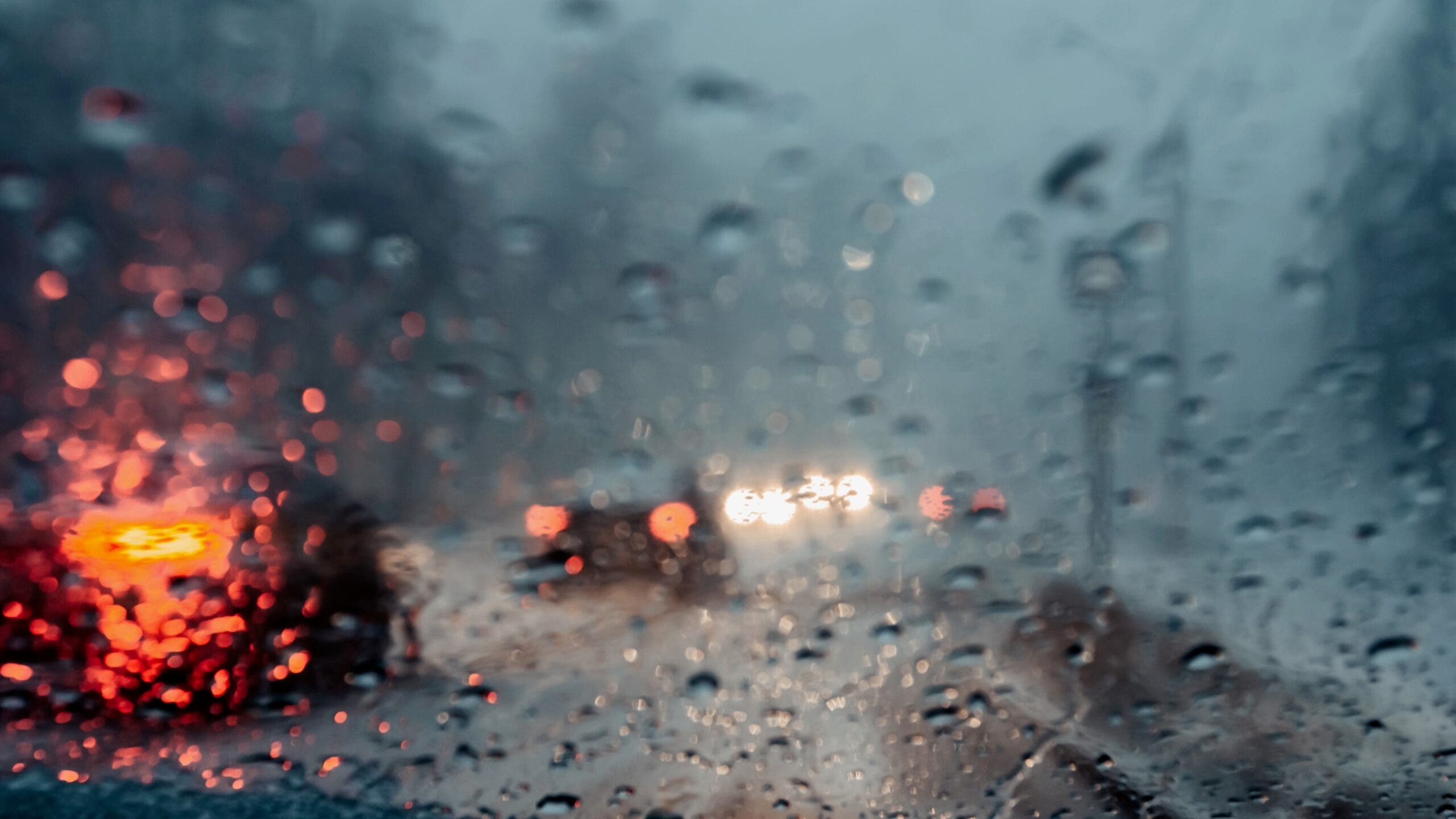 Blurred drizzle on the windshield in the evening.