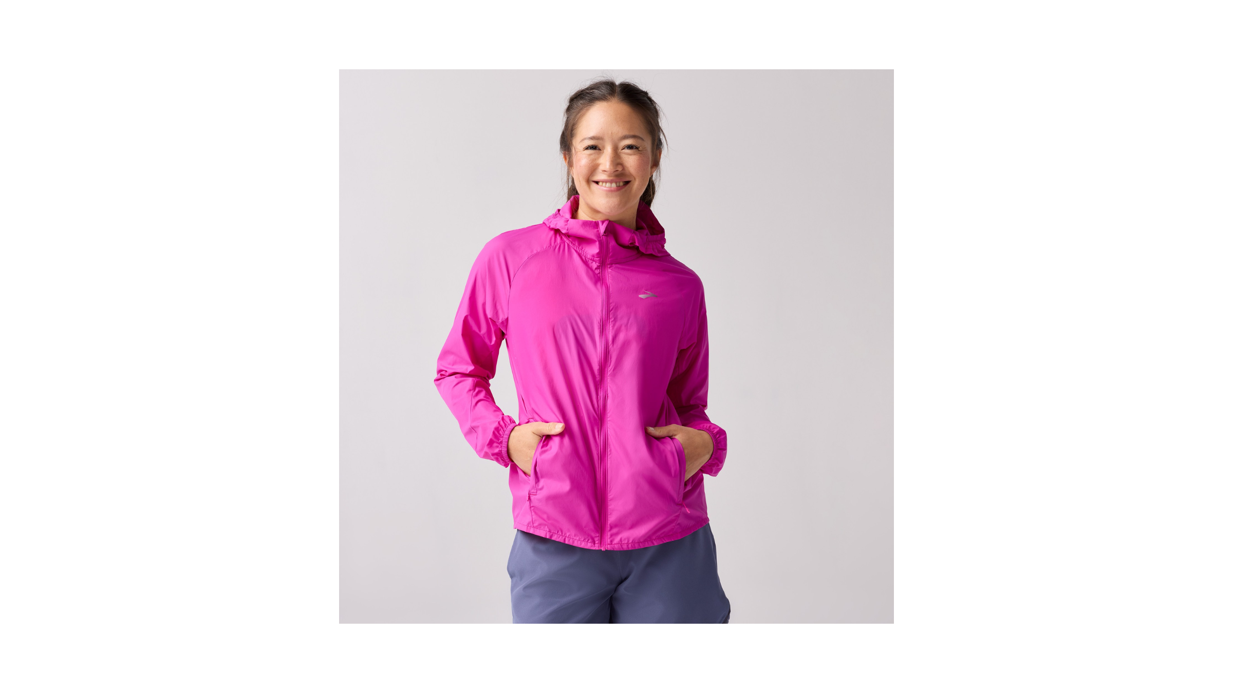 Outside's Best Value Winter Running Jacket in 2026, the Brooks Canopy Packable Jacket shown in bright pink magenta on a female model