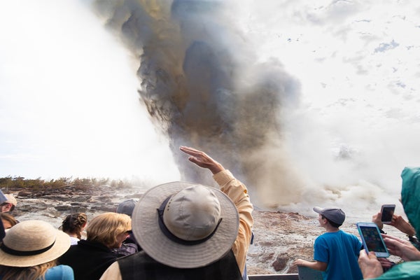 A crowd of people witness the rare eruption of Steamboat Geyser, the largest active geyser in the world