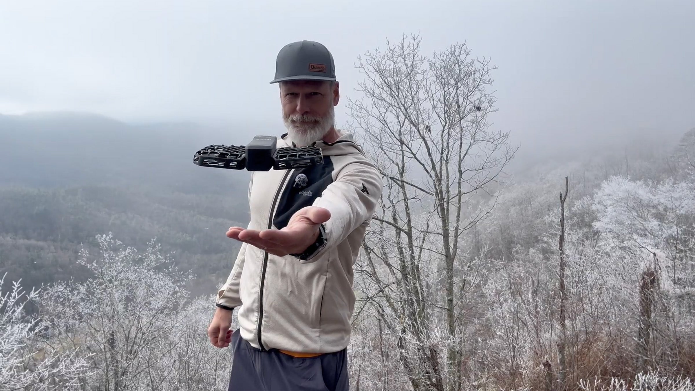 Man standing on cliff with HoverAir X1 drone hovering above his outstretched hand