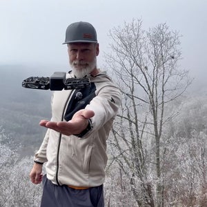 Man standing on cliff with HoverAir X1 drone hovering above his outstretched hand