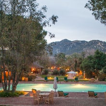 A resort pool at the foot of a mountain during dusk.
