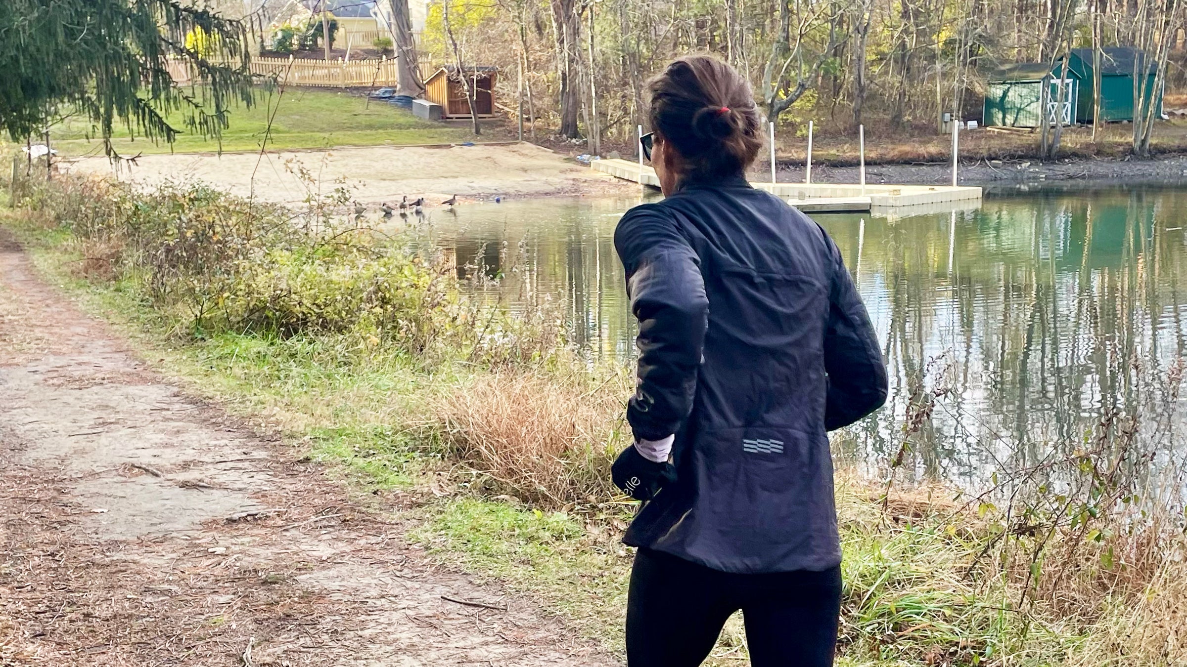 Outside writer Lisa Jhung testing the best winter running jackets for women in 2026, running on a trail next to a pond