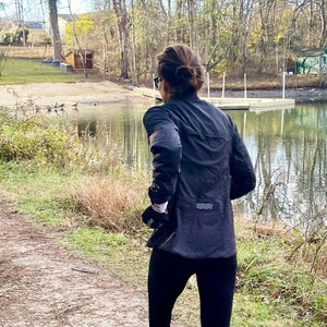 Outside writer Lisa Jhung testing the best winter running jackets for women in 2026, running on a trail next to a pond