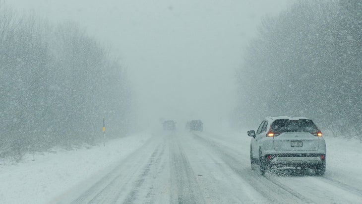 Vehicles drive along a snowy road
