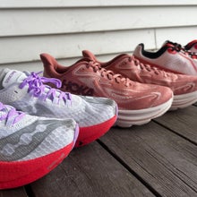 A lineup of four pairs of running shoes arranged from left to right on a wooden deck, showing different brands and colorways for comparison in a story by author Maggie Slepian.