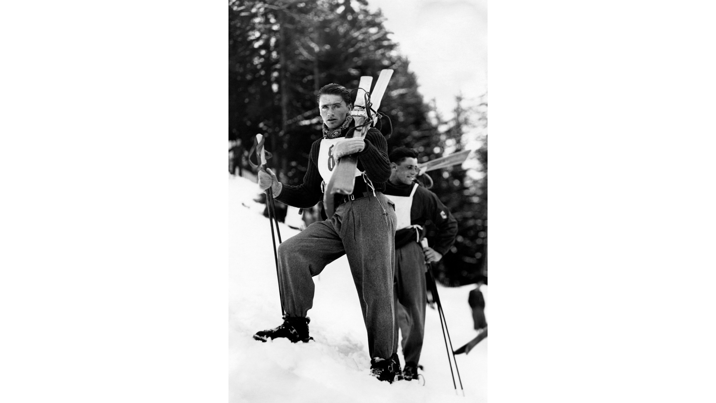 French skier Émile Allais demonstrates an early evolution in winter olympics gear, standing in the snow wearing innovative, tighter-fitting "pantalons en fuseau" rather than the loose woolen trousers common at the 1936 Games.