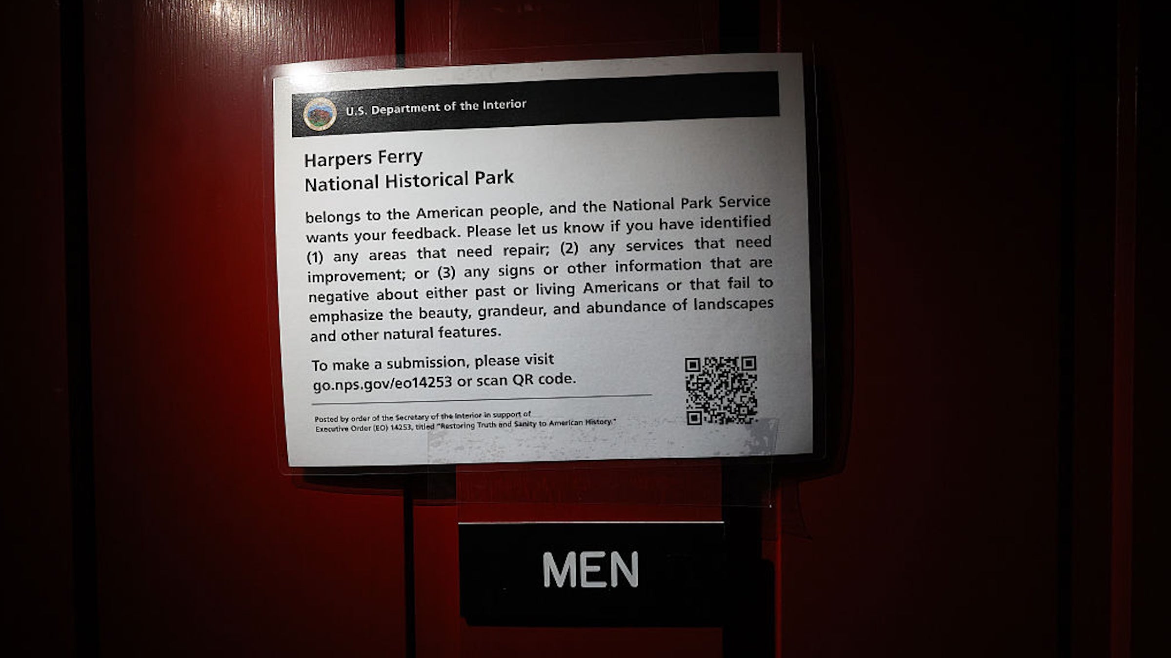 A sign on a restroom door asking visitors to report negative signage is shown at the Harpers Ferry National Historical Park in 2025