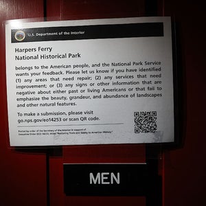 A sign on a restroom door asking visitors to report negative signage is shown at the Harpers Ferry National Historical Park in 2025