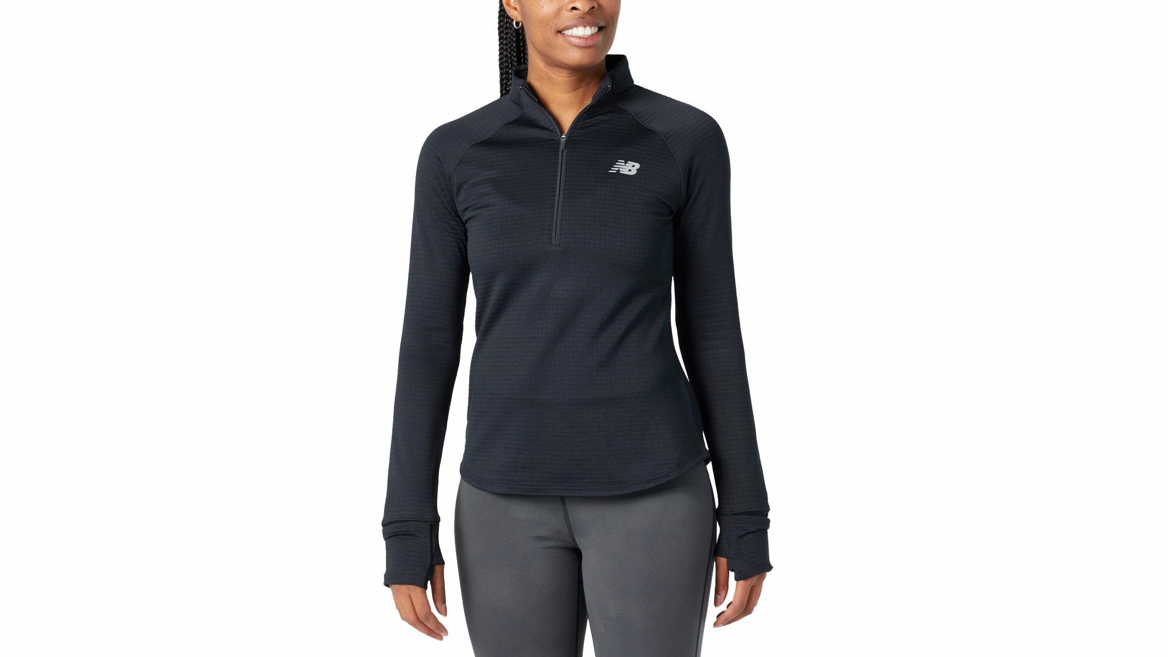 A woman wears the black New Balance Athletic Heat Grid Half Zip, a textured running layer with a stand-up collar and thumbholes, while posing against a white background.