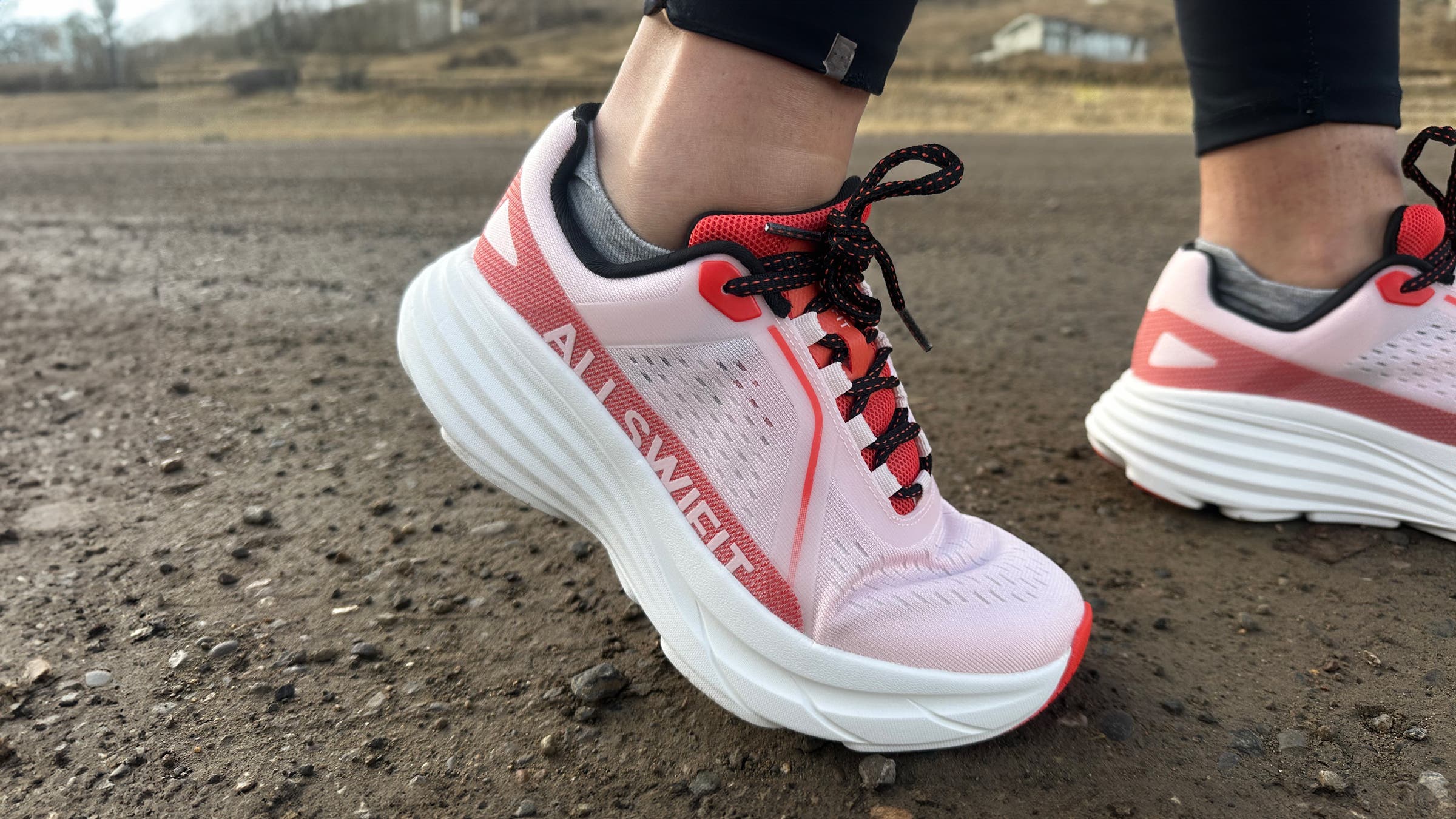 Close-up of Nortiv 8 Allswifit ActiveAiry running shoes on a gravel surface, highlighting the cushioned white midsole, breathable pink upper, and lace-up fit during an outdoor run.
