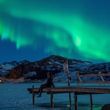 A woman observing northern lights (Aurora borealis), on the Lofoten Islands, in Bostad, in the arctic circle in northern Norway.