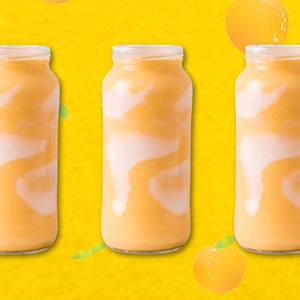 orange julius smoothie on an orange background with oranges floating around