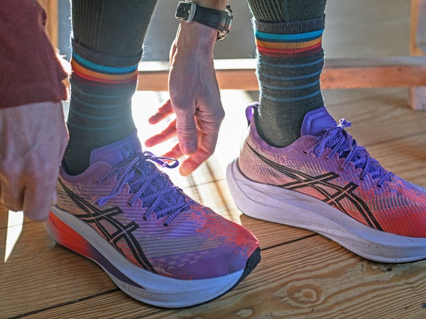 Runner lacing shoes over mid-height striped running socks.