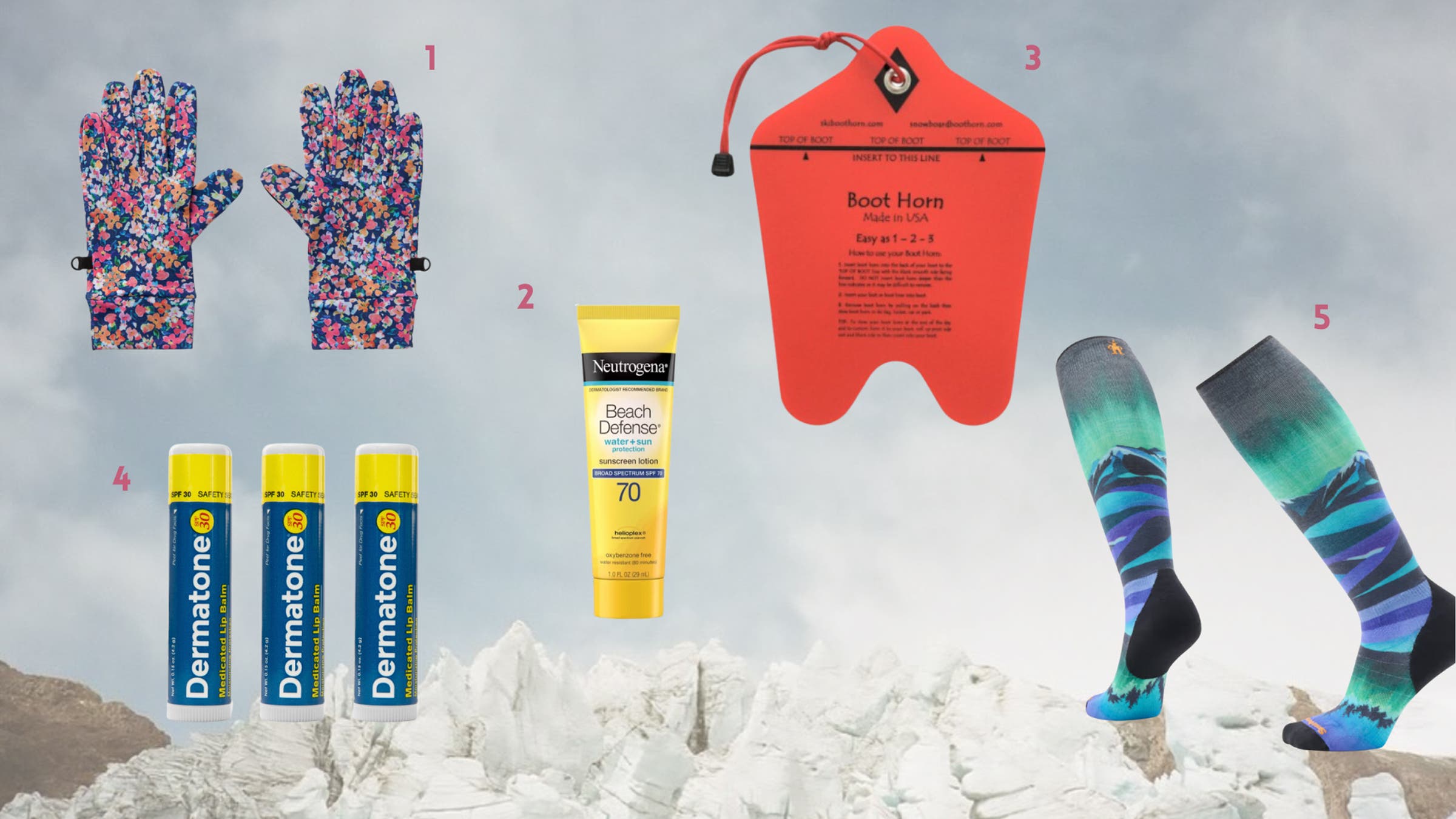 Flat lay of pregnancy ski gear accessories including floral insulated gloves, Neutrogena Beach Defense SPF 70 sunscreen, a red ski boot horn tool, Dermaton SPF lip balm tubes, and colorful over-the-calf ski socks displayed against a snowy mountain backdrop.