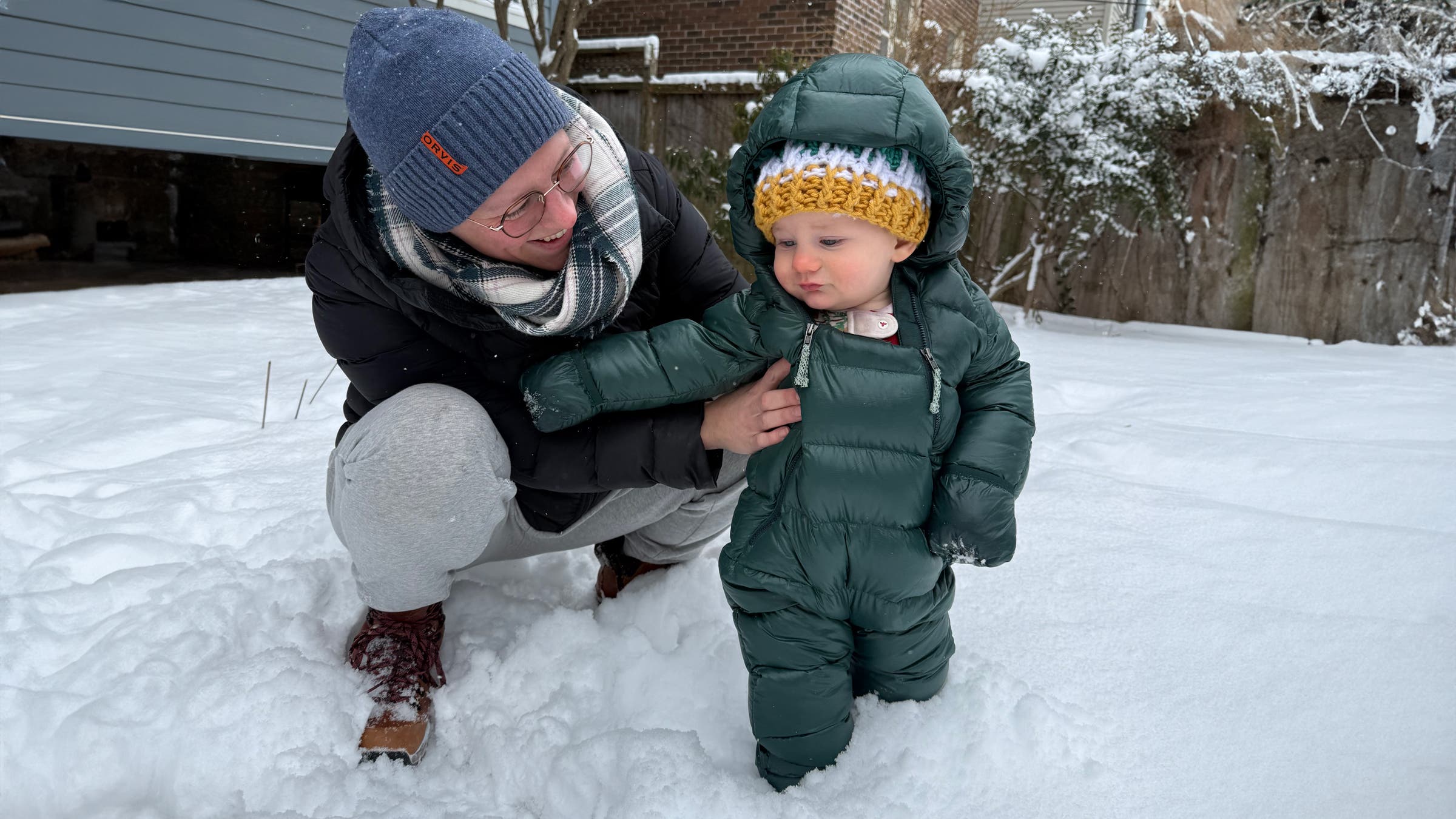Baby playing in snow in warm down Patagonia Infant Hi-Loft Down Sweater Bunting
winter snowsuit dark green.