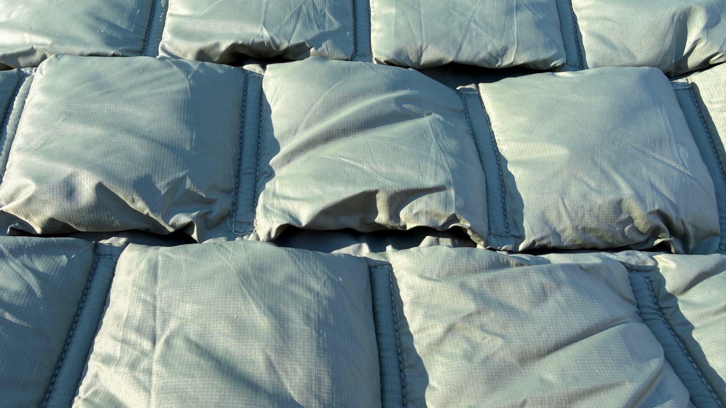 Close-up detail of the quilted insulation and stitch-free baffle design on the Mountain Equipment Oreus Hooded Jacket, highlighting the loft and fabric texture of this lightweight synthetic jacket built for cold-weather performance.