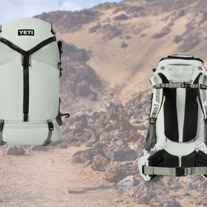 Front and back views of a white YETI Skala 60 hiking backpack shown against a rocky, desert mountain trail background.