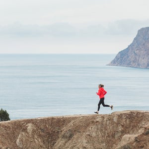 Woman trail running in mountains with scenery view of sea and coastline