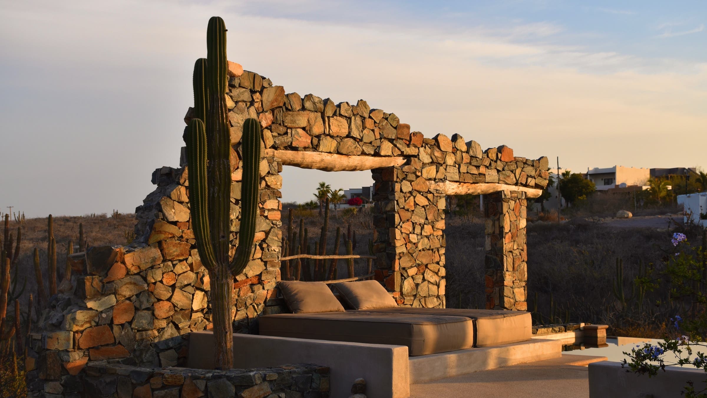 Stone cabana next to a saguaro cactus.