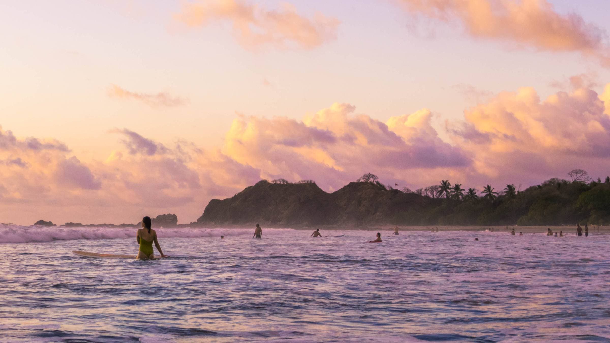 Surfers wait for a weave during sunset on Guiones Beach, Costa Rica.
