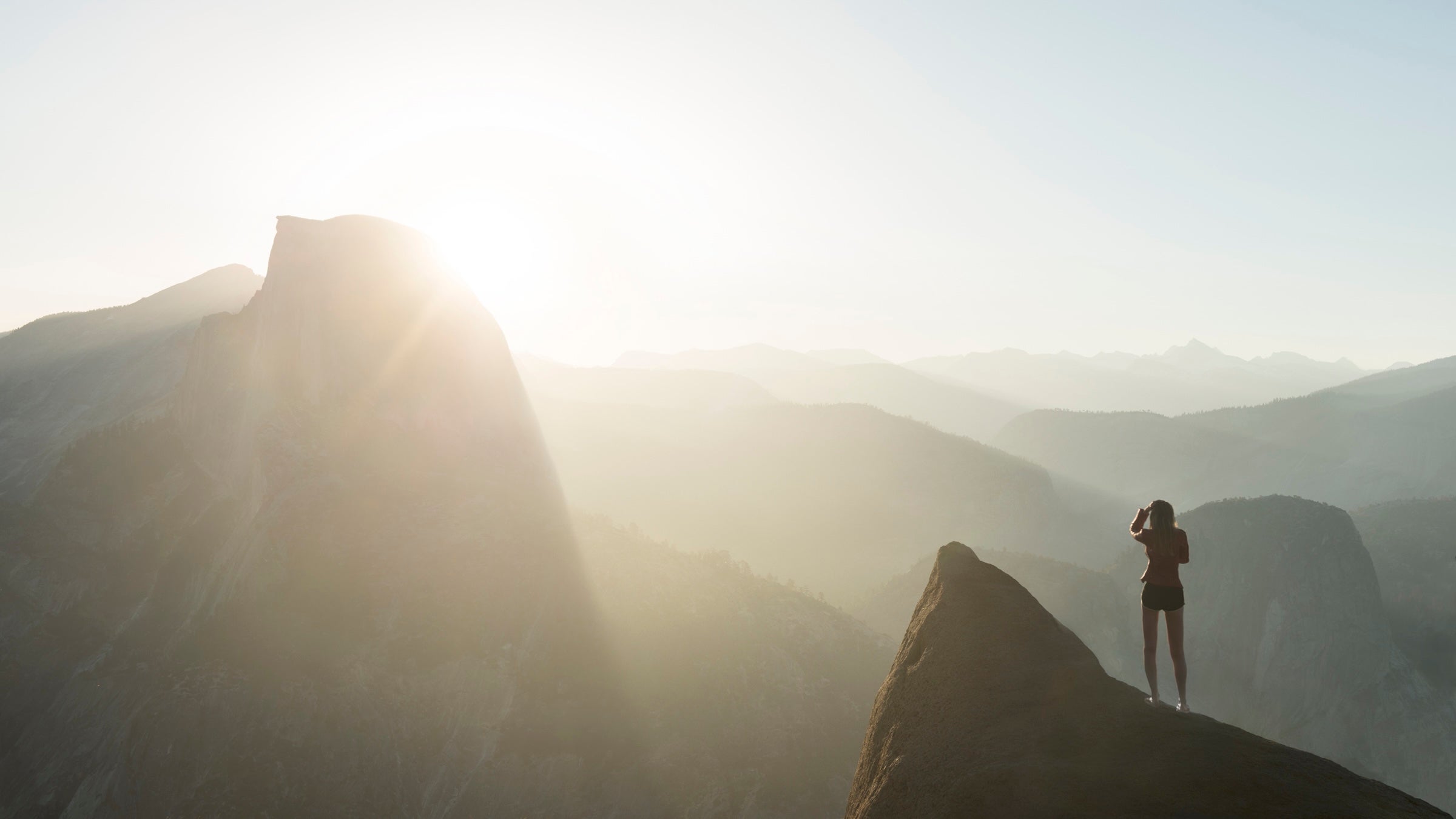 A woman stands along a cliff in Yosemite National Park