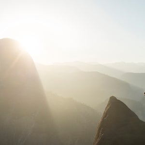 A woman stands along a cliff in Yosemite National Park