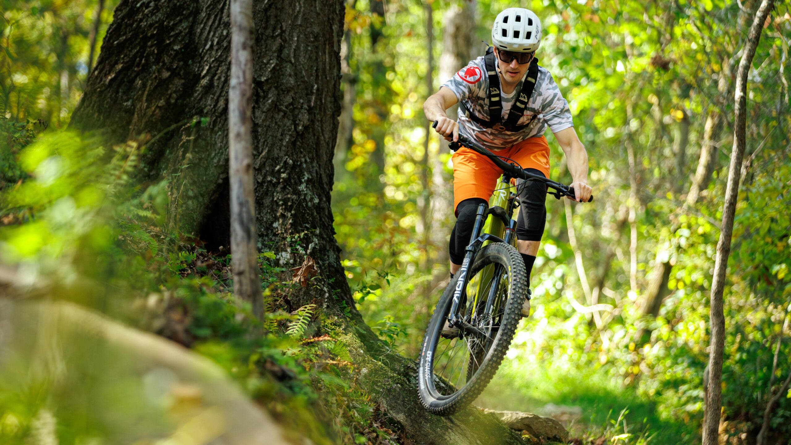 Mountain biker mid-jump on Revel Rascal trail mountain bike on forrest trail