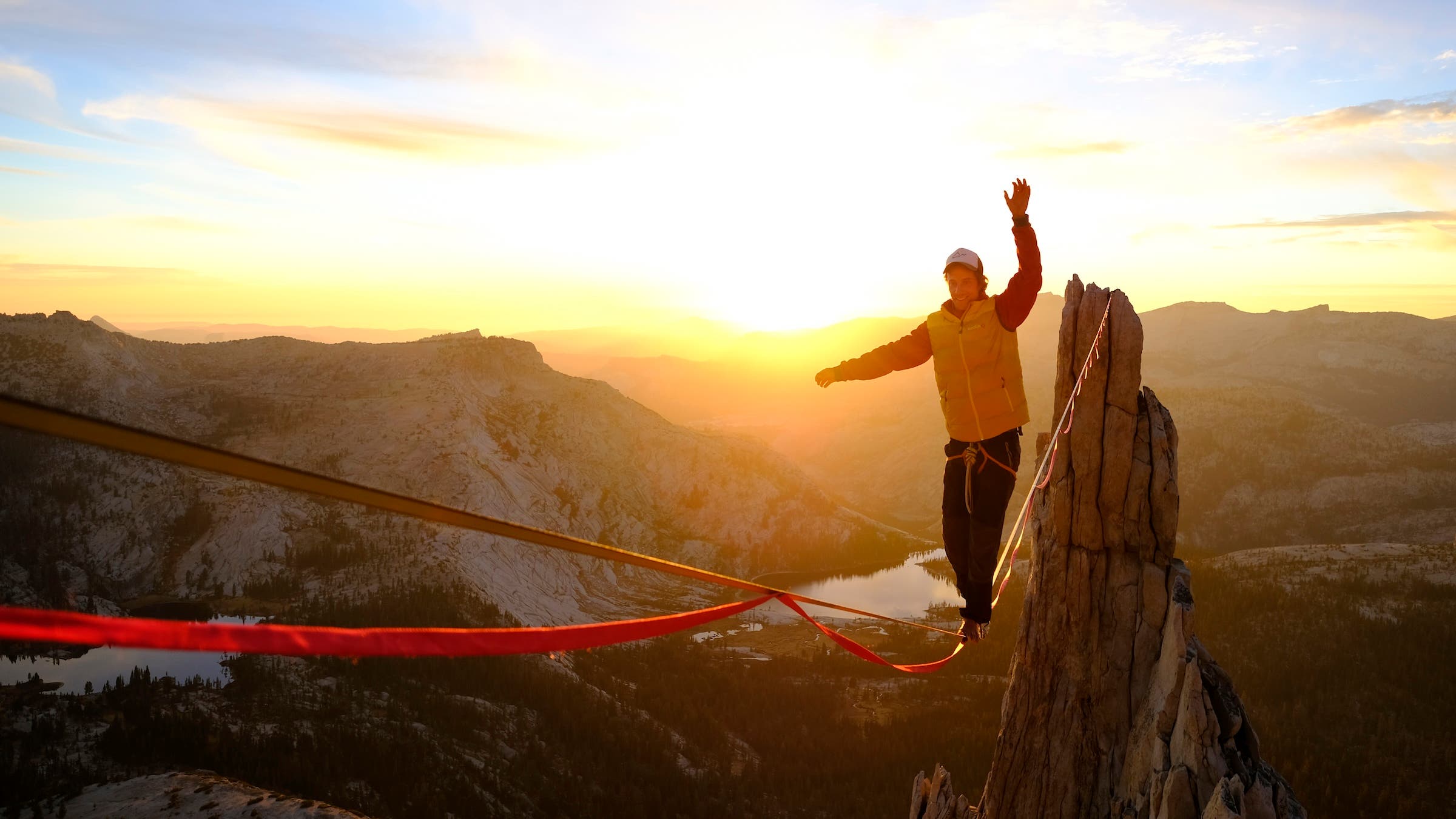 Kühne is shown walking across a red highline strung between two canyon peaks