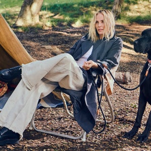 Charlize Theron sitting at a campsite with her dog.