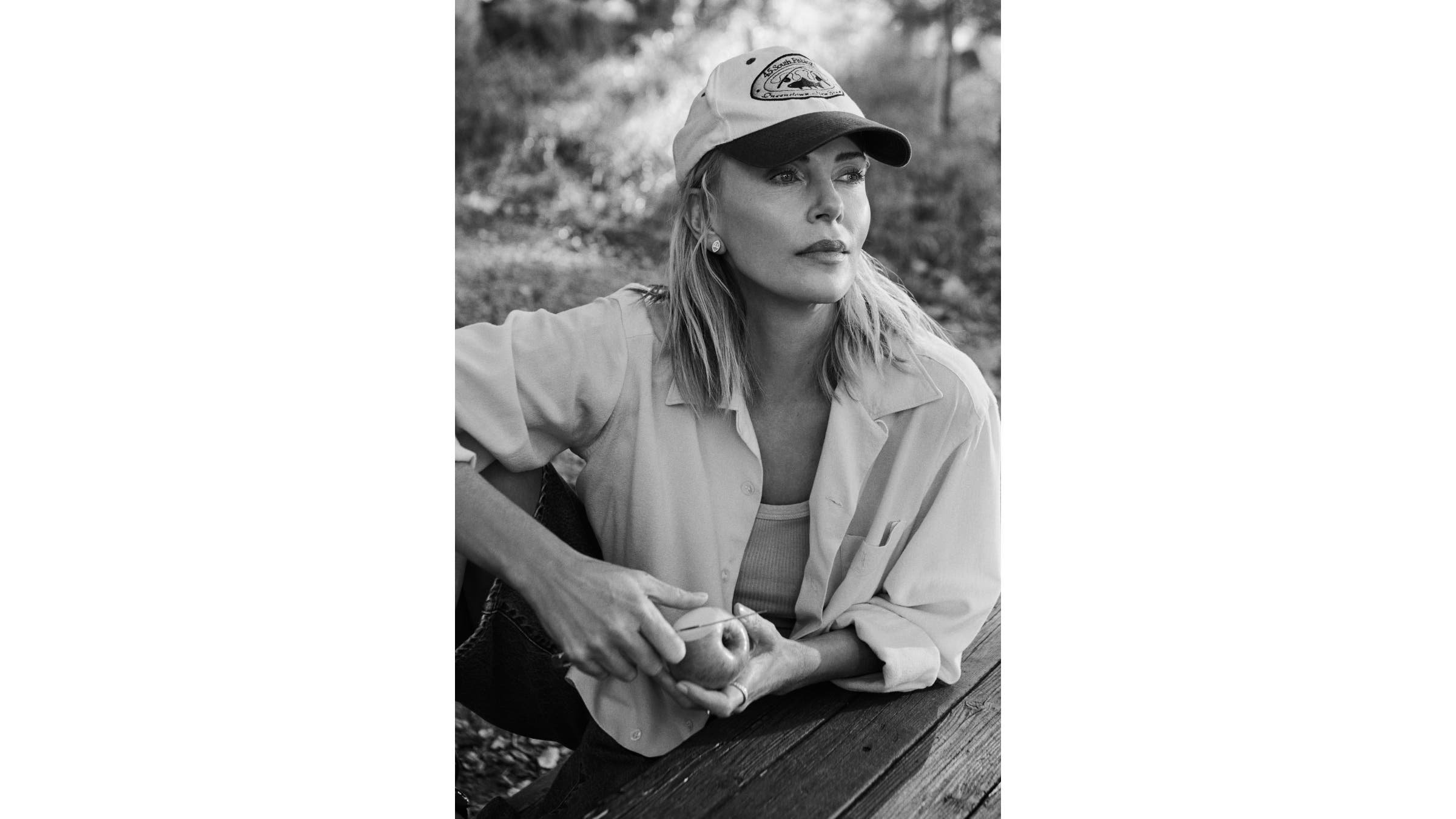 Black and white portrait of Charlize Theron holding an apple.