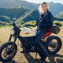 Charlize Theron sitting on a Ducati in the mountains.