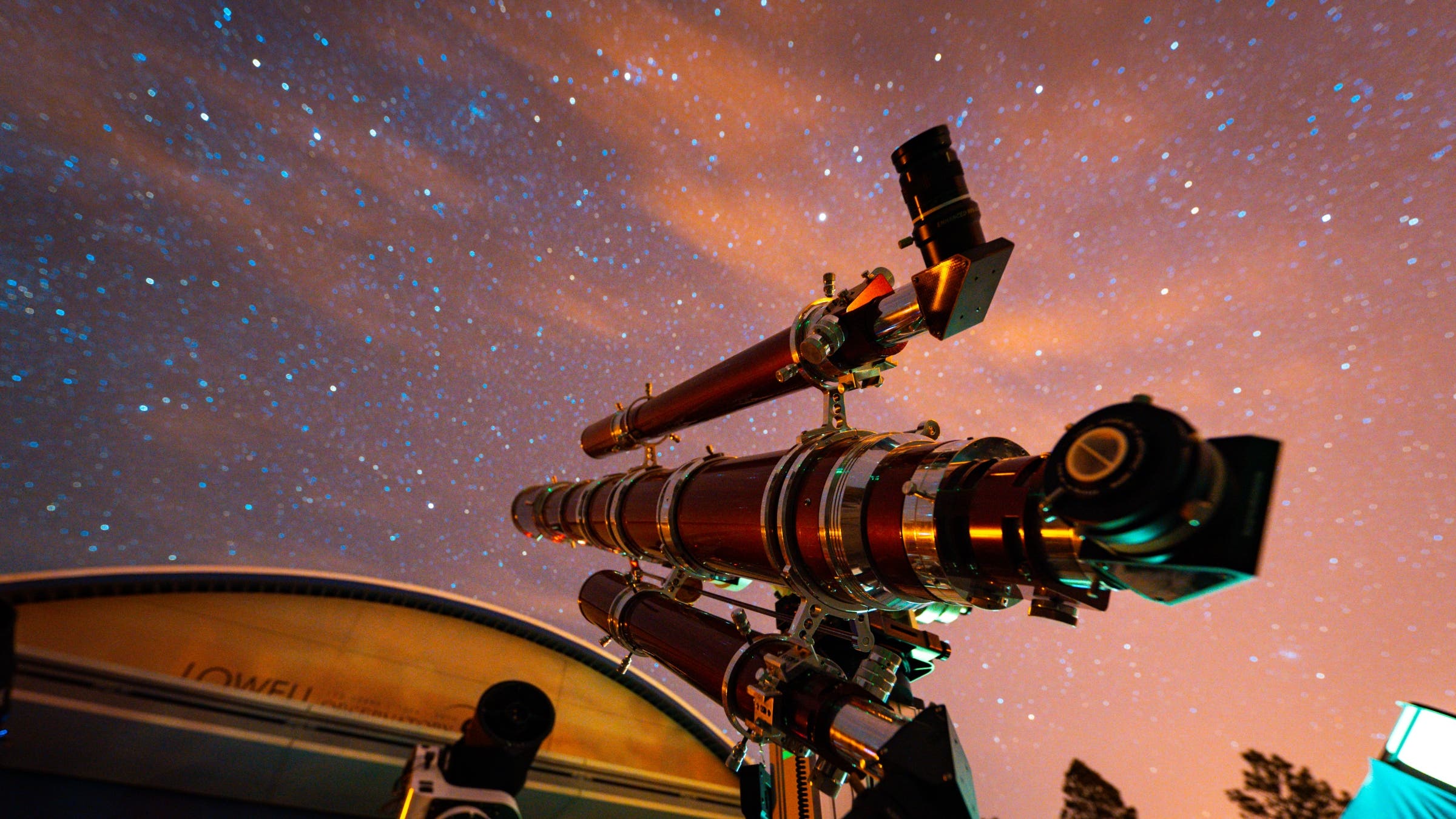A telescope against a partly cloudy night sky.